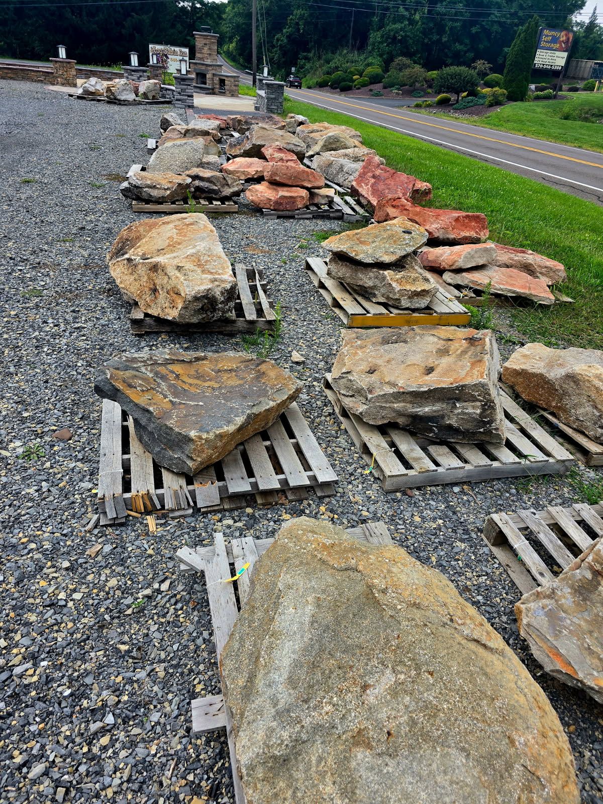 Large rocks laid on metal grates along a roadside beside a green grassy shoulder and pavement.