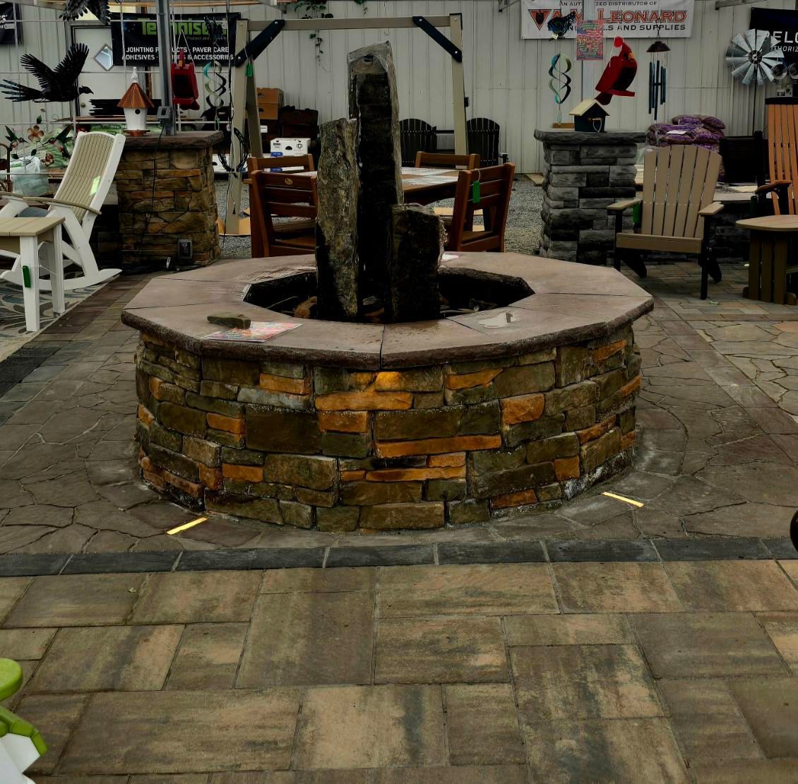 Rustic courtyard with a brick planter fountain and stone paving, surrounded by outdoor chairs and tables.