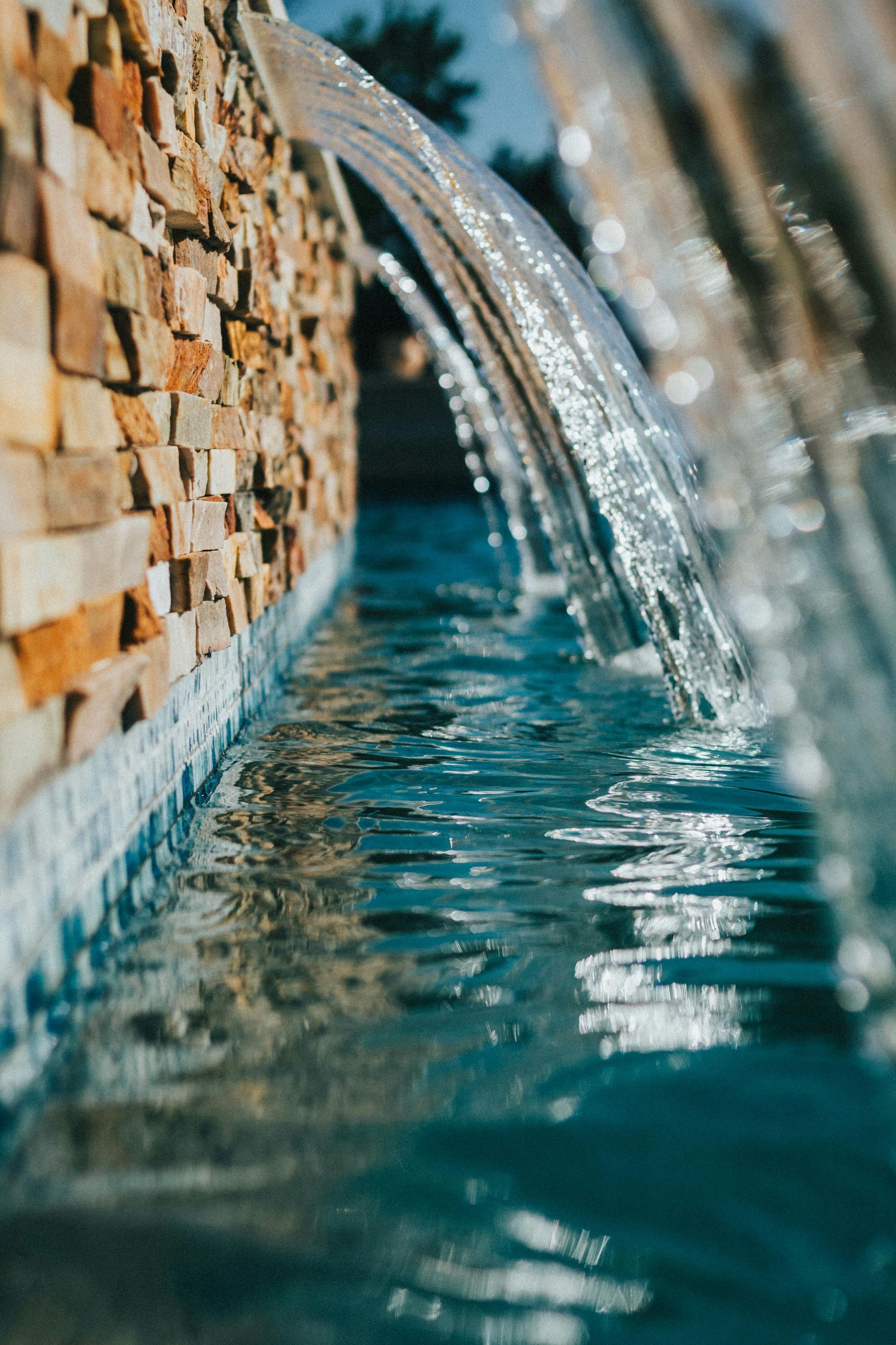 Close-up of water flowing over stacked stone into a turquoise pool