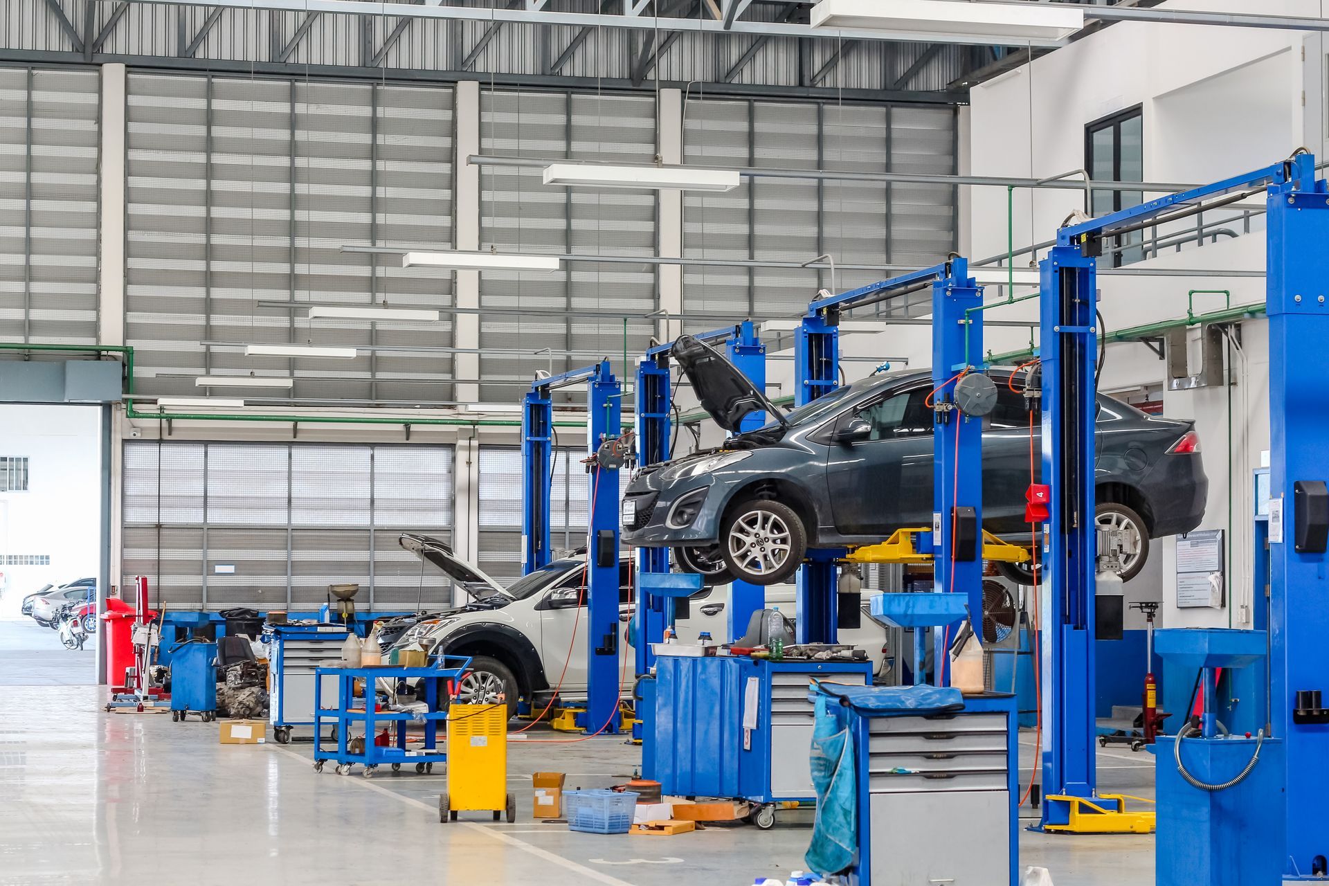 Car being lifted on a blue hydraulic repair lift inside an auto service garage