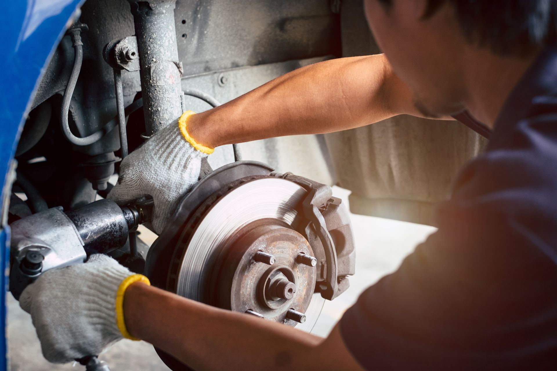 Mechanic using tools to work on a car brake rotor and hub assembly. Mechanic using tools to work on a car brake rotor and hub assembly.