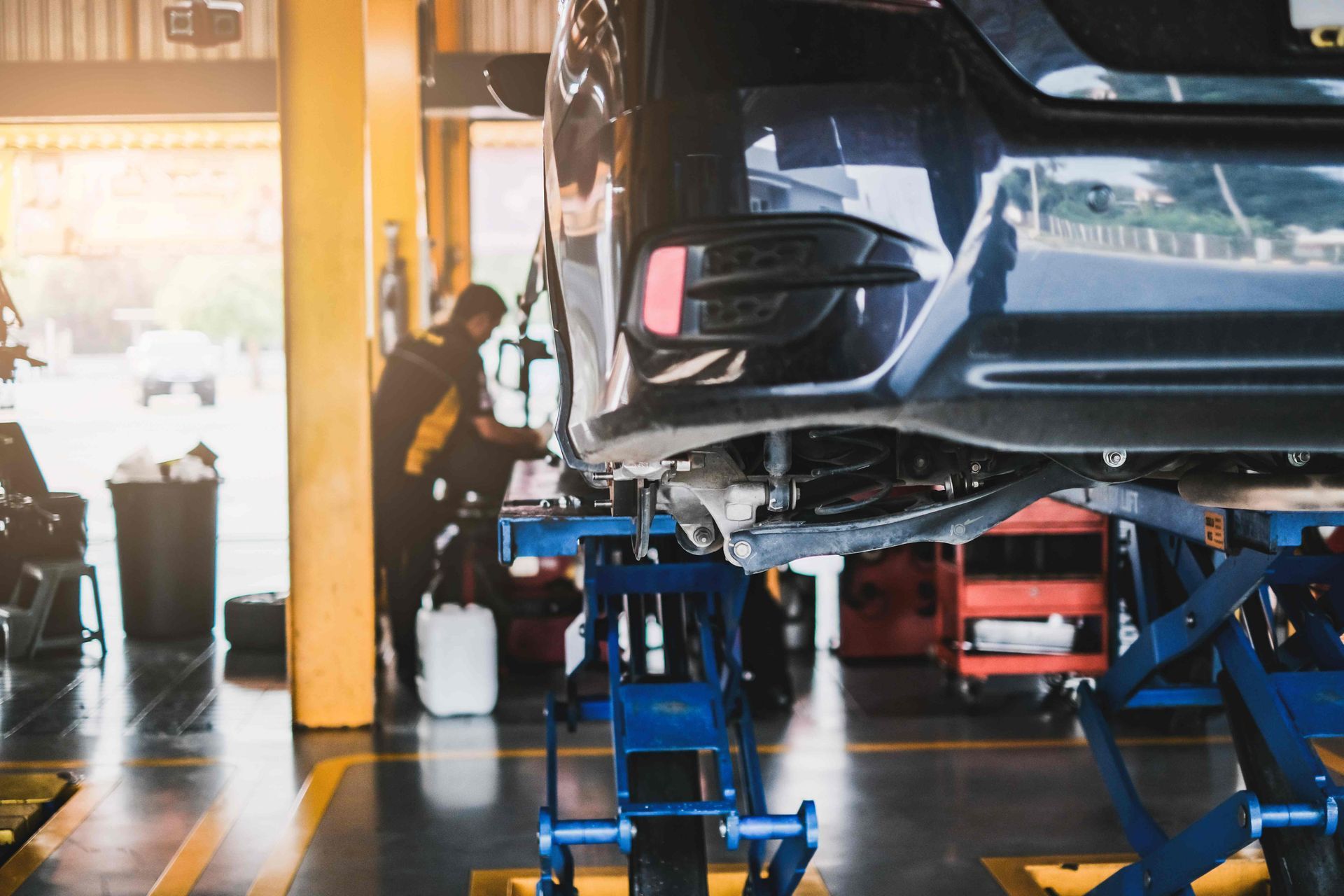 Car in for service mot replacing wheel and repairment, in vehicle work shop with suspension.