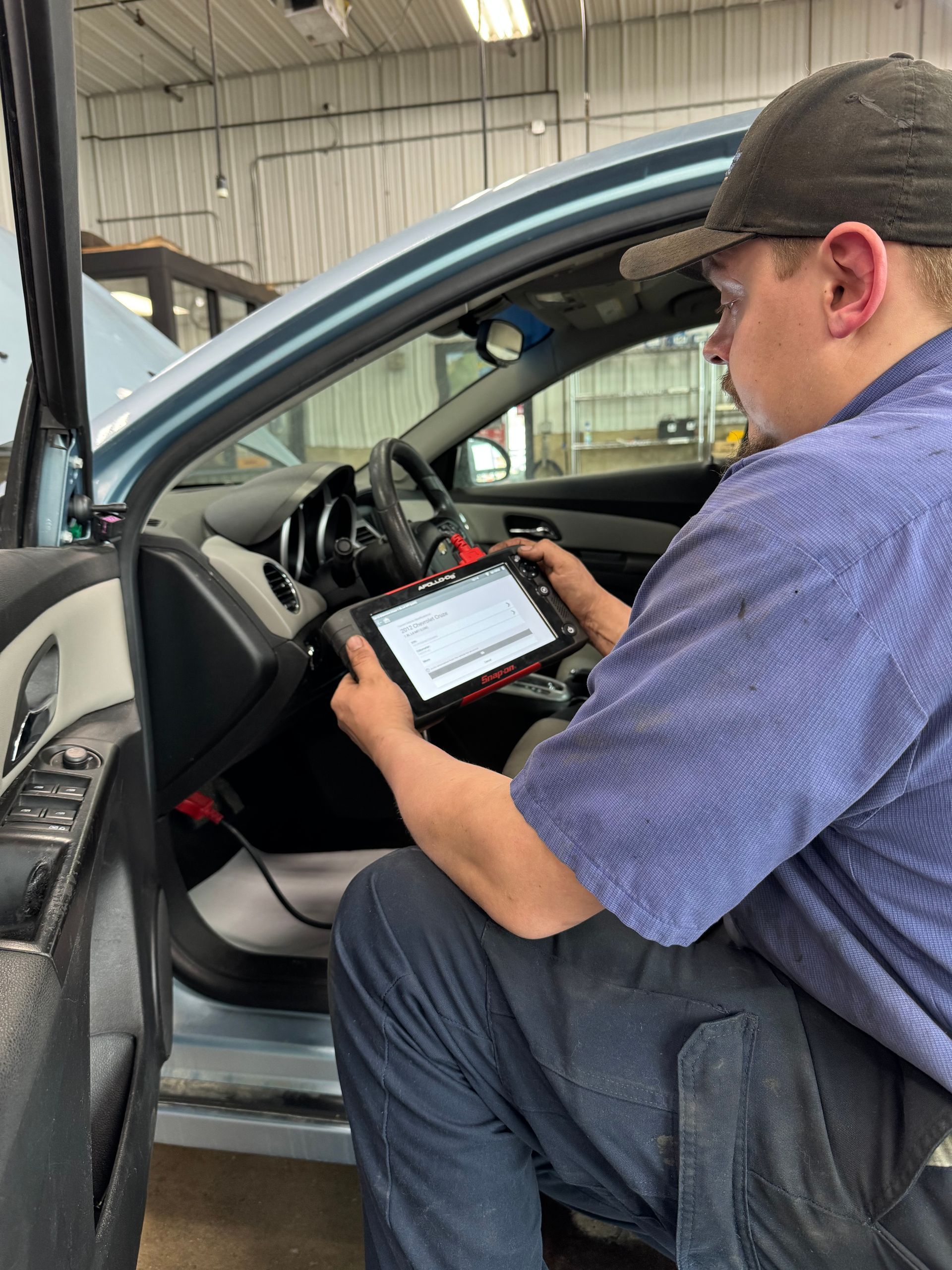 Mechanic using a tablet to inspect a car interior in a repair shop