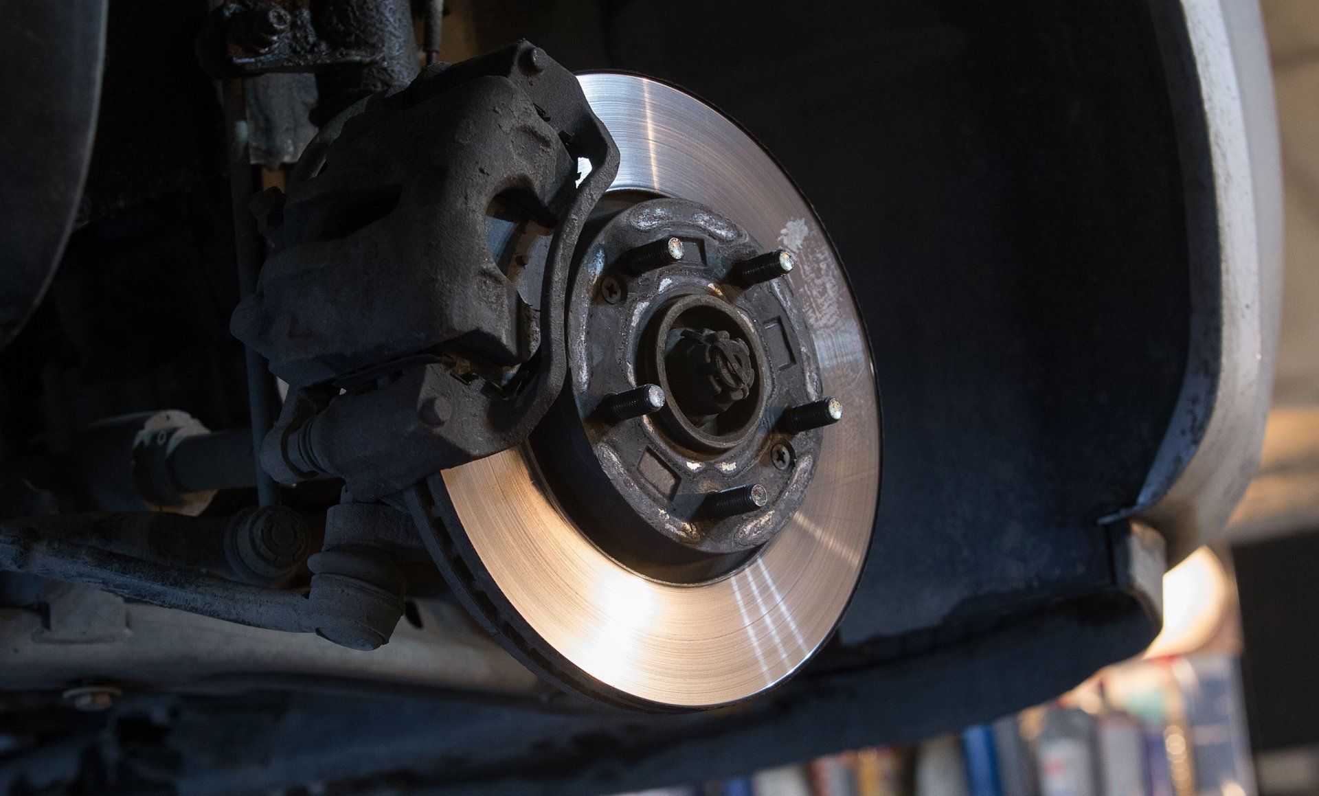 Close-up of a car brake disc and caliper inside the wheel well, with the wheel removed.