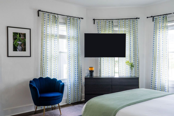Bedroom with bed, large abstract art, TV, air conditioner, and bright window.