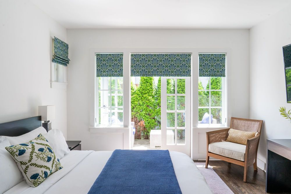 Modern white bedroom with a bed, nightstands, and sheer curtains.