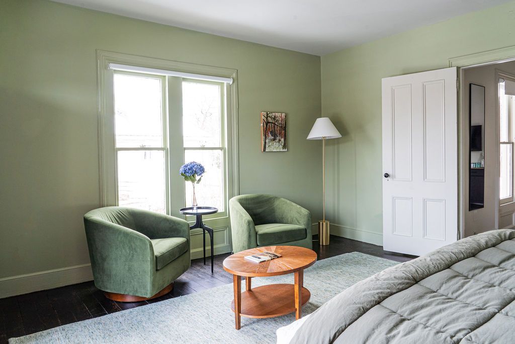 Bedroom with bed, television, open doorway to another room with seating.