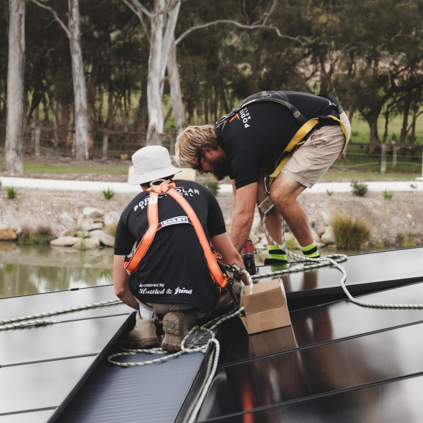 Two Men Are Working on A Solar Panel and One of Them Is Wearing a Shirt that Says Power Project — Podium Solar in Cameron Park, NSW
