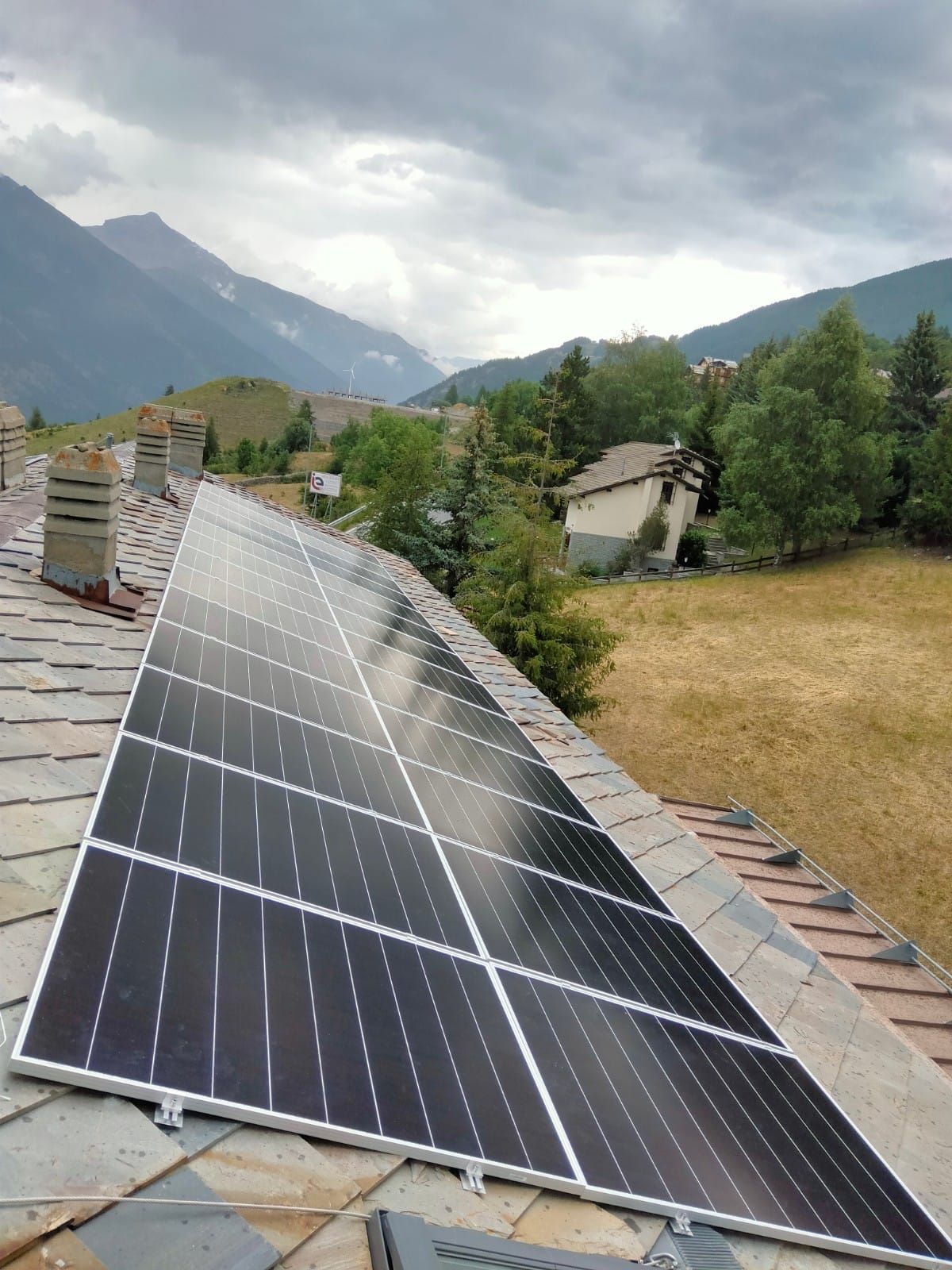 altra immagine di tetto con pannelli fotovoltaici e montagne sullo sfondo