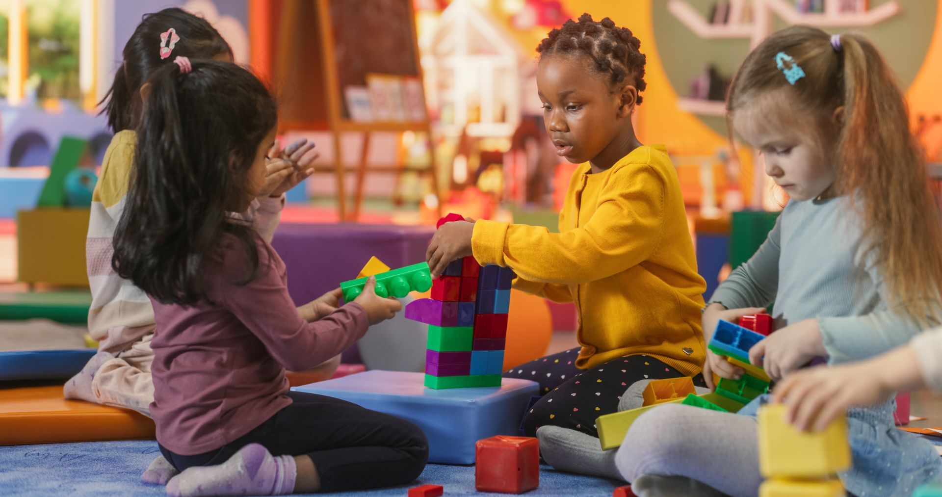 Children playing with colorful blocks on a classroom rug.