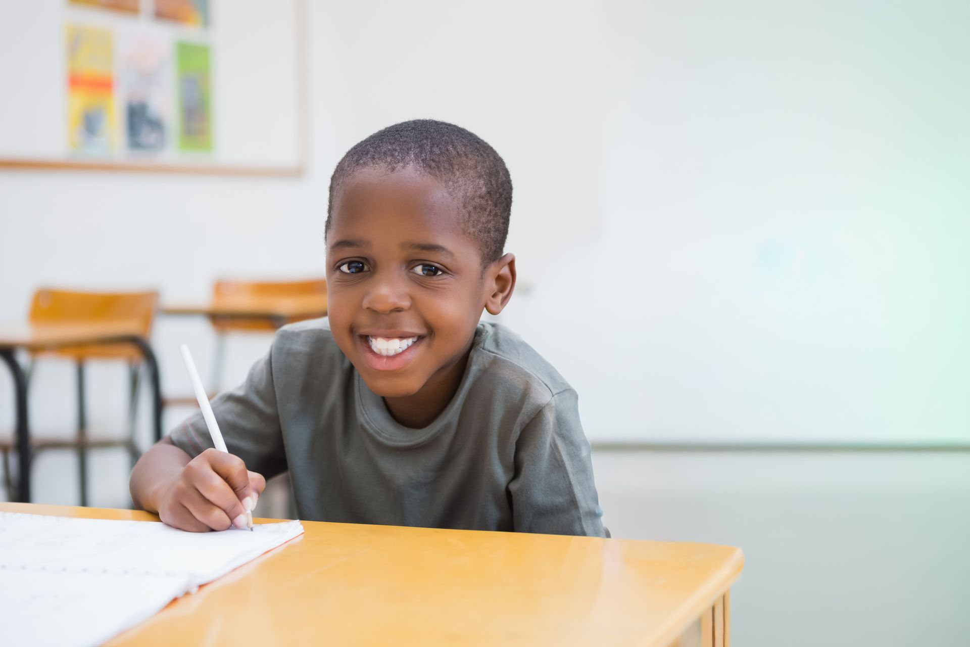 Smiling student writing at a desk in a classroom