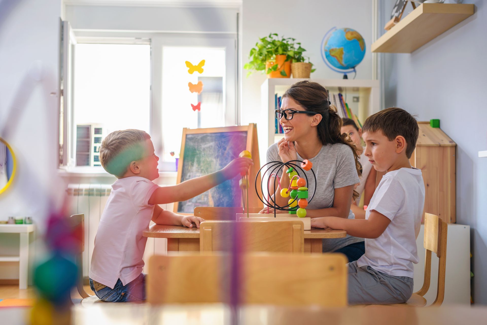 Teacher and children in a bright classroom, drawing and working together at a table