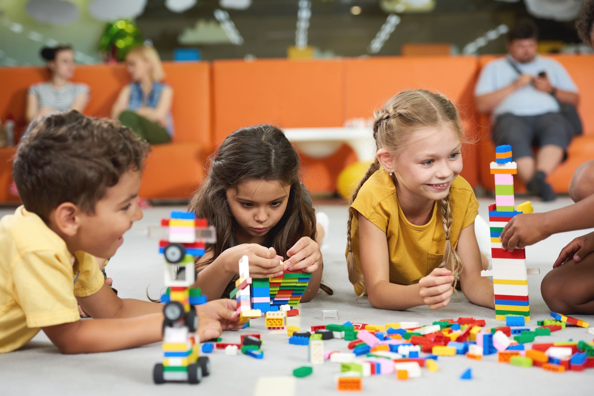 Children building colorful blocks on the floor in a bright play area