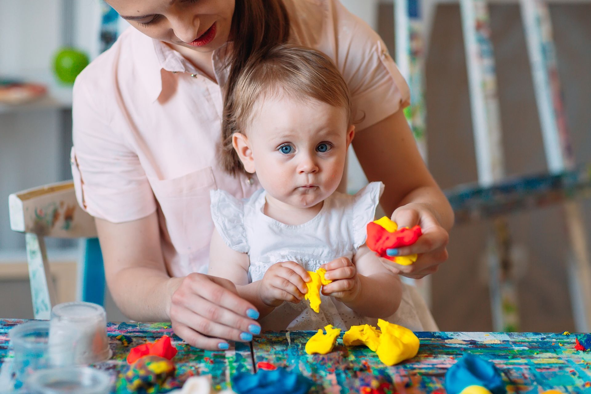 Adult and toddler playing with colorful dough at a table indoors