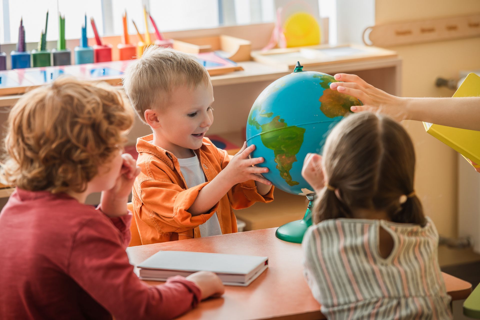 Children in a classroom reaching for a globe during a lesson