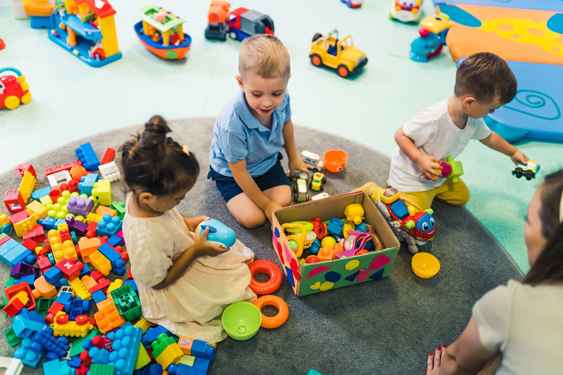Children playing with colorful blocks and toy vehicles on a classroom floor