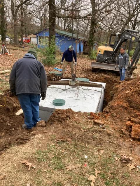 A group of men are working on a septic tank in a yard.
