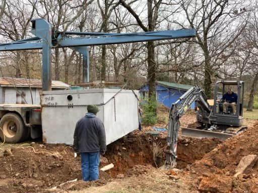 A man is standing in the dirt next to a truck and a crane.