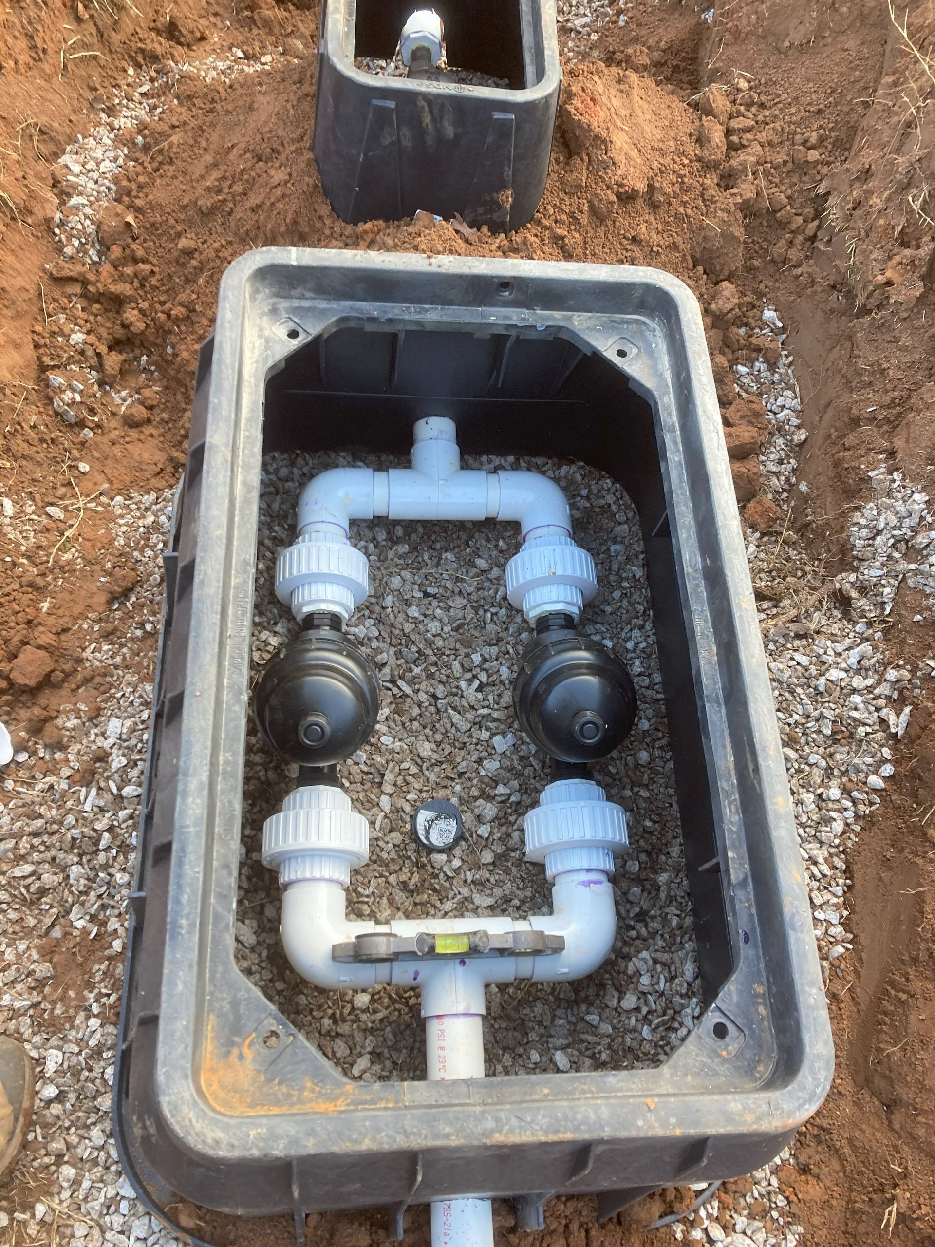 A box with pipes in it is sitting in the dirt.