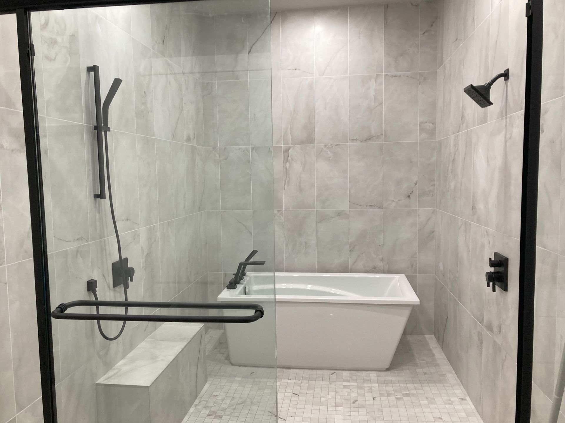 A bathroom with a tub and a shower with a glass door.