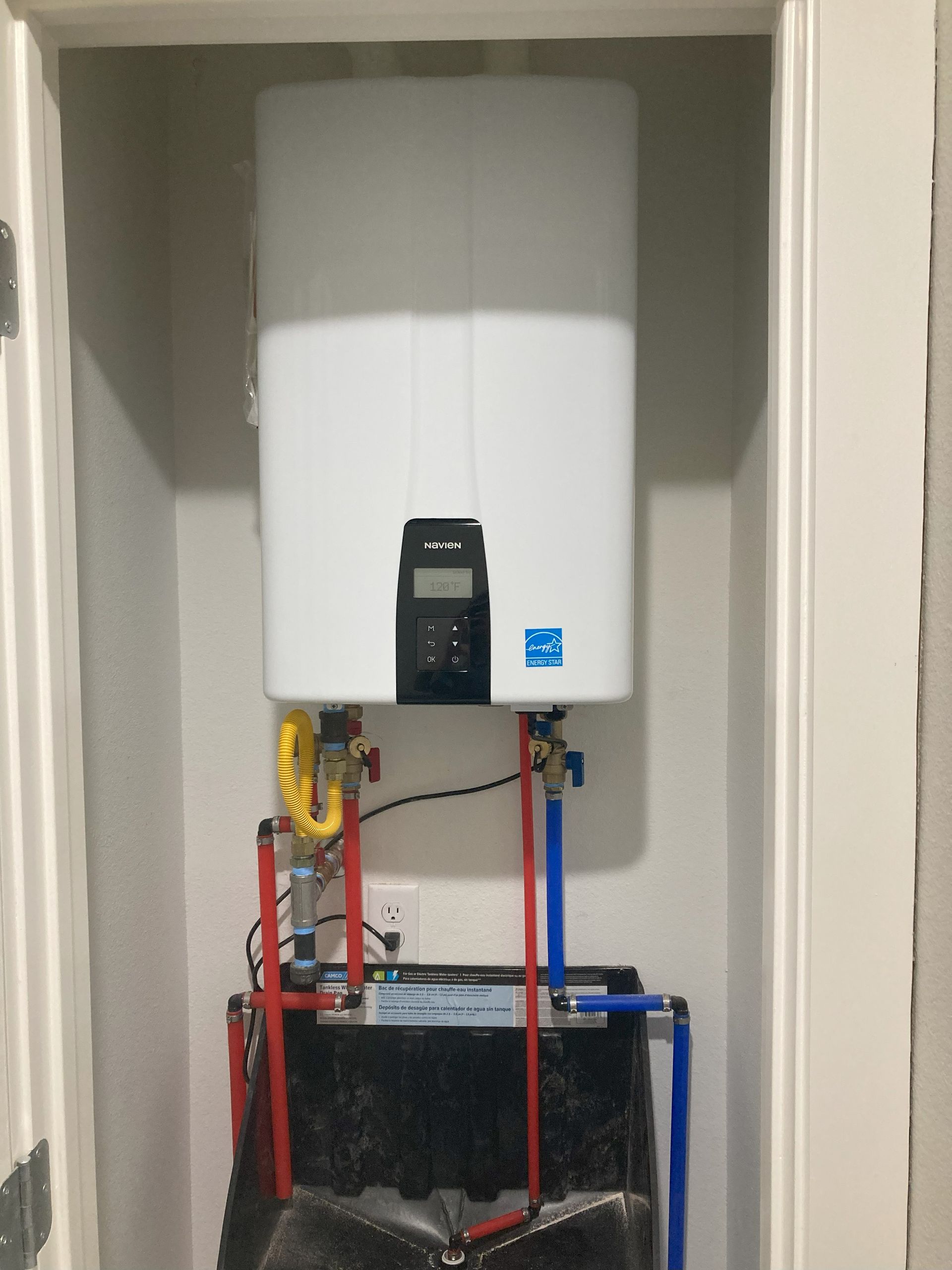 A white water heater is mounted to the wall in a closet