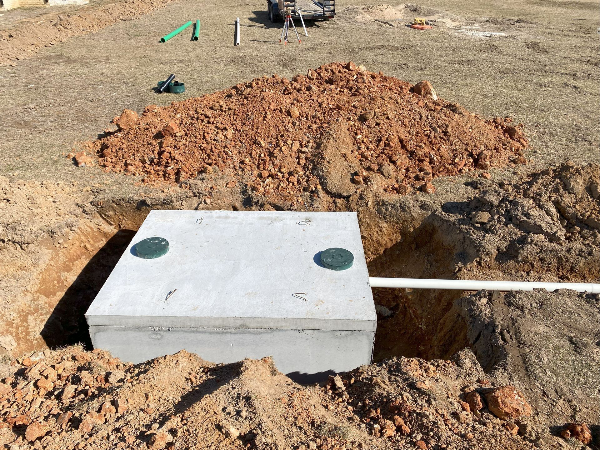 A septic tank is sitting in the middle of a dirt field.