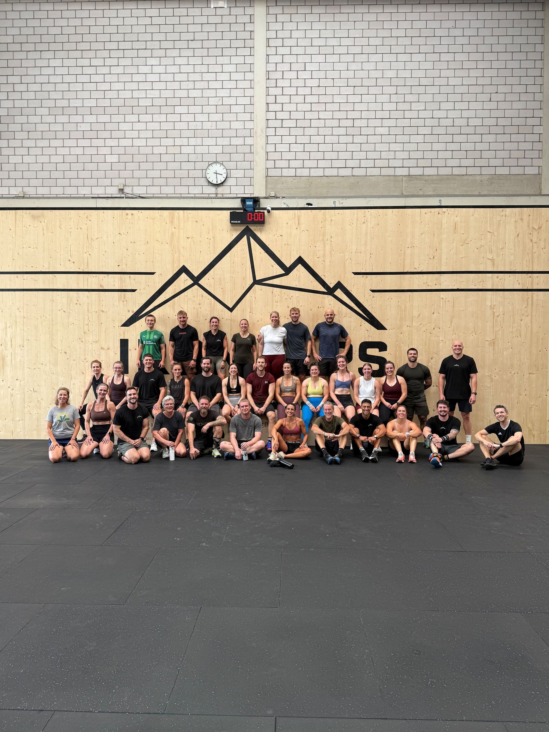 Menschen liegen auf Gymnastikmatten neben einer Langhantel und scheinen sich nach dem Training auszuruhen.