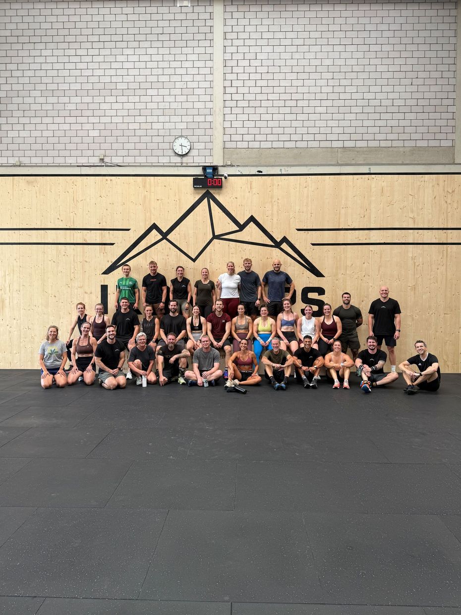 Menschen liegen auf Gymnastikmatten neben einer Langhantel und scheinen sich nach dem Training auszuruhen.