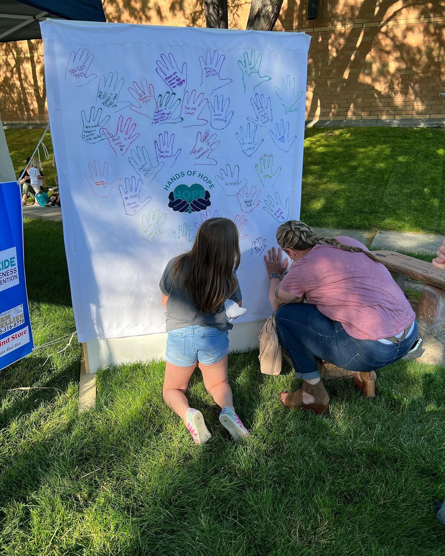 A woman and a child are kneeling in front of a large white board.