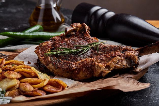 Gegrilltes Steak mit Bratkartoffeln, Chilischoten und Kräutern.