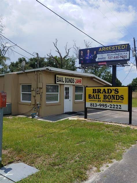 Small bail bonds office with signs reading “Brad’s Bail Bonds” and “Arrested” by the roadside