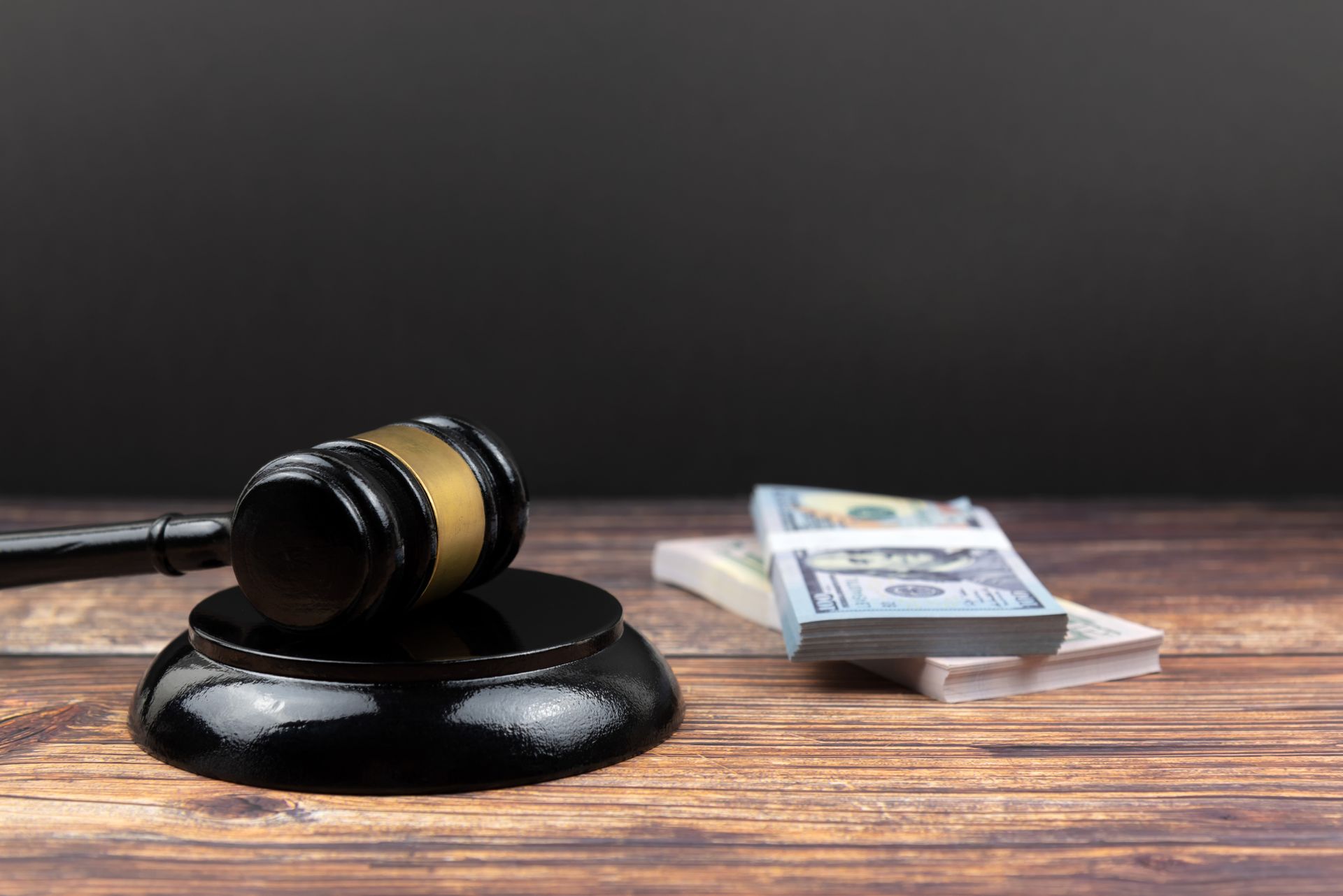 A judge 's gavel on a wooden table next to a pile of money