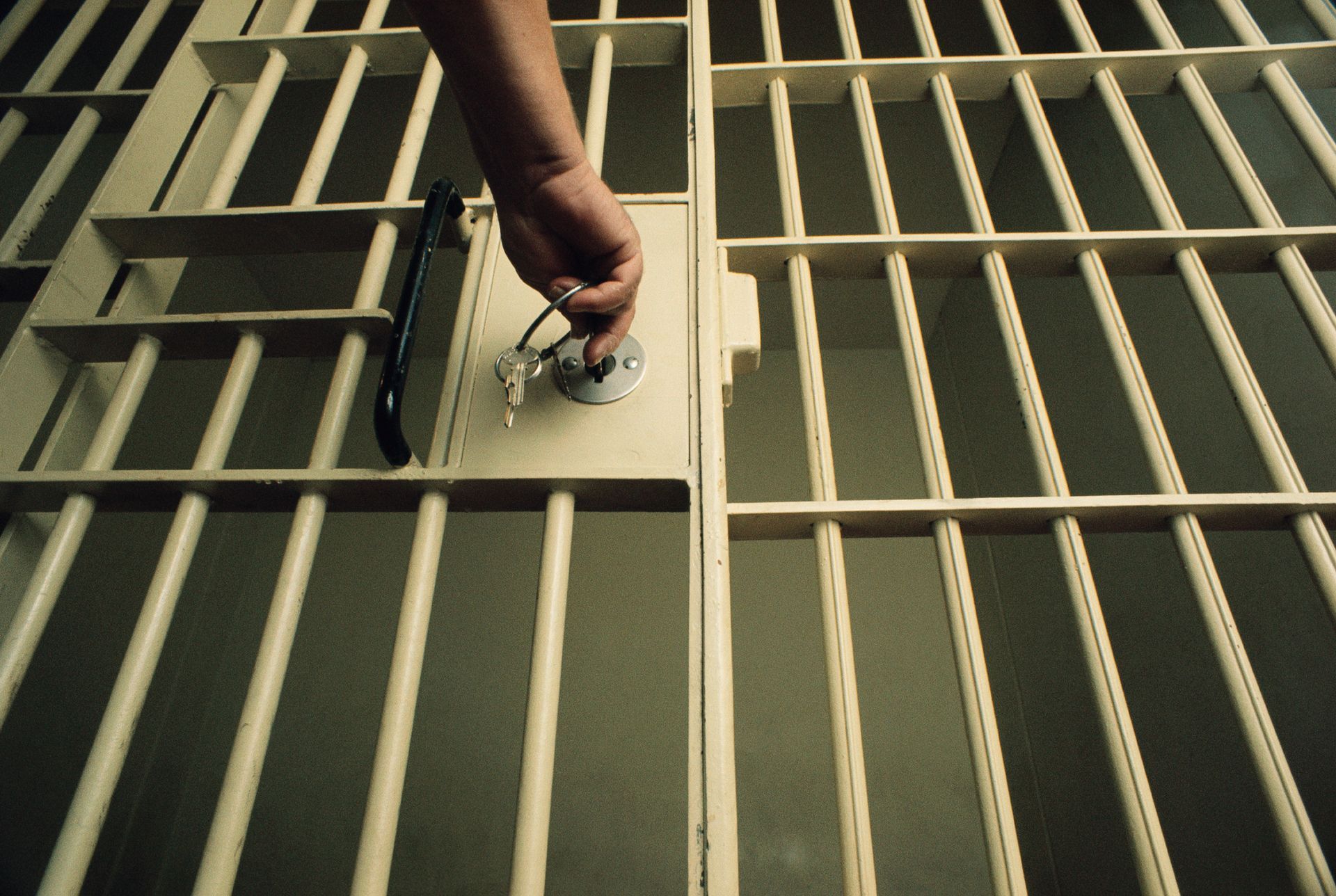 Man Using A Key To Open A Jail Cell — Land O Lakes, FL — Brad’s Bail Bonds Man Using A Key To Open A Jail Cell — Land O Lakes, FL — Brad’s Bail Bonds