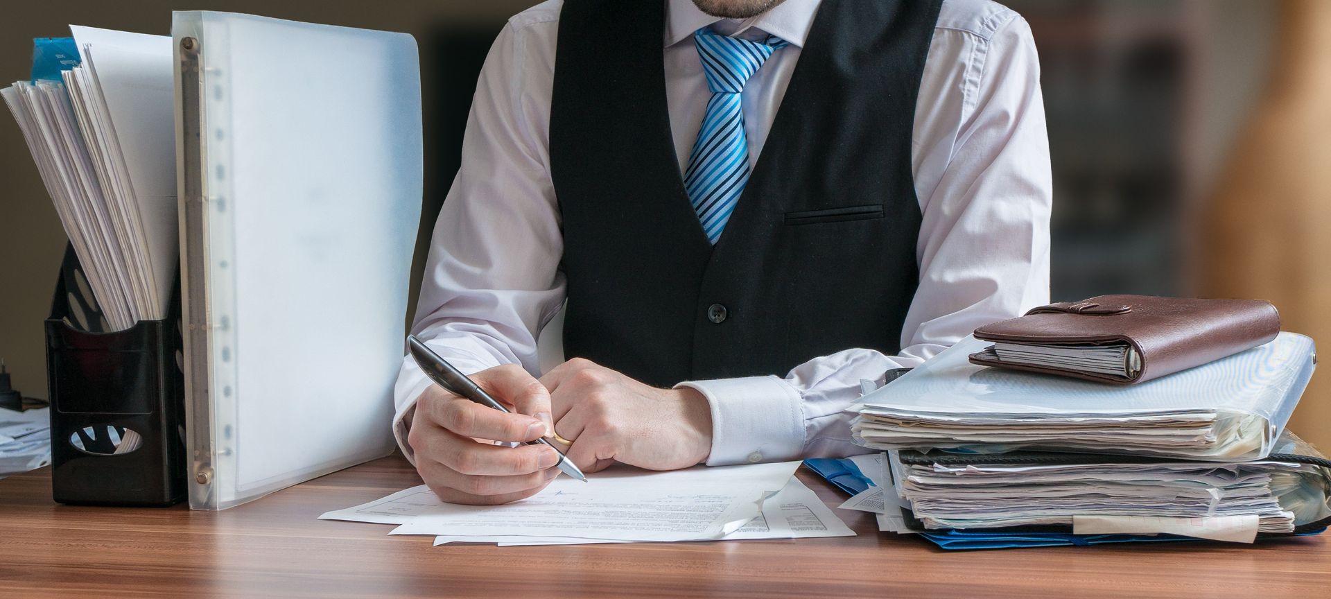 A man is sitting at a desk writing on a piece of paper.