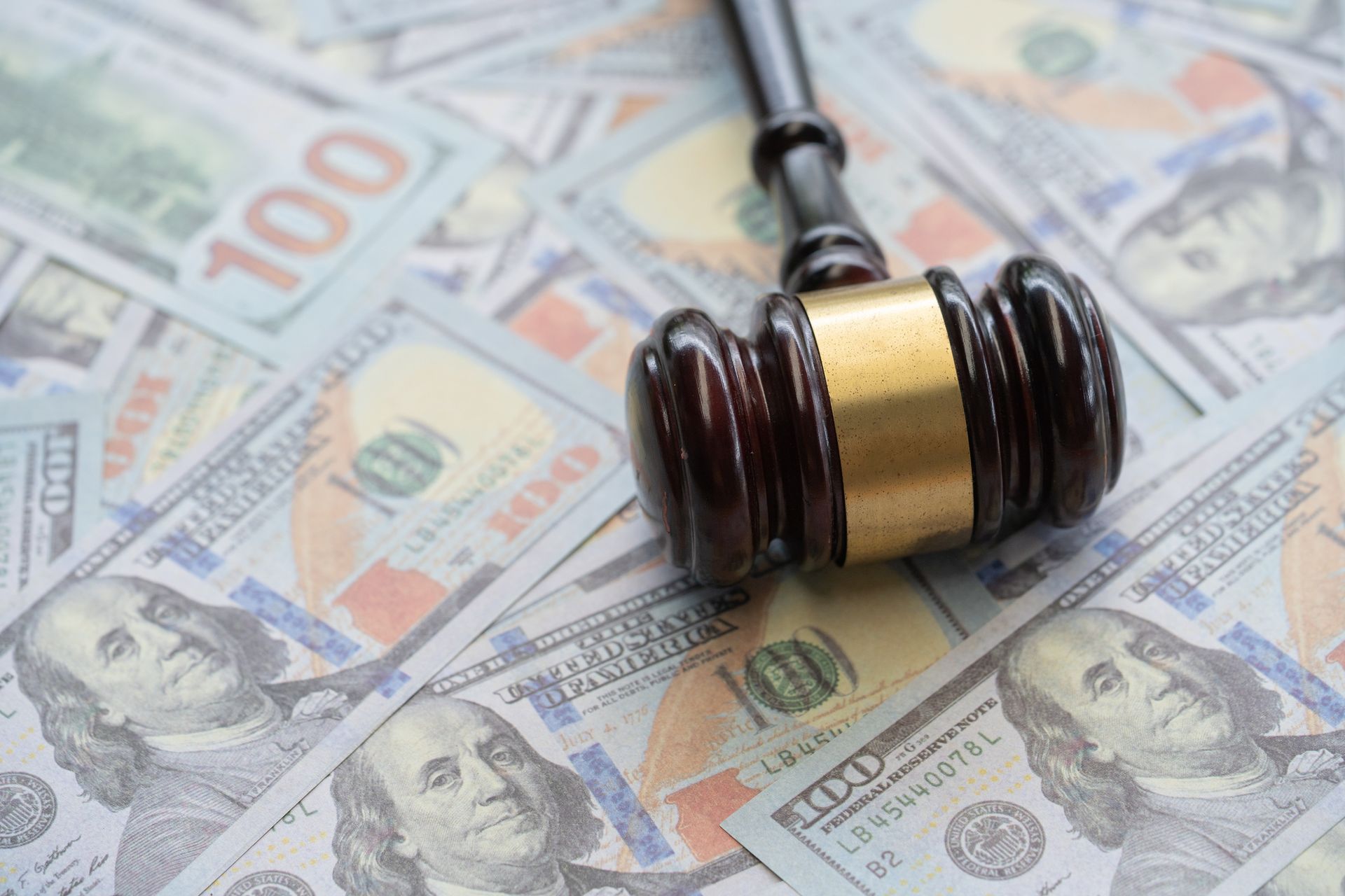 A wooden judge 's gavel is sitting on top of a pile of money.