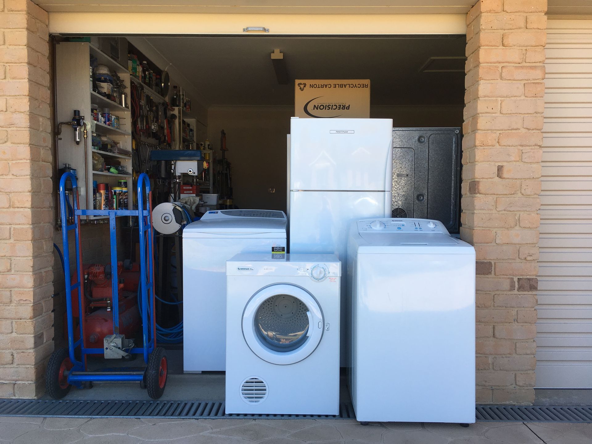 A garage entrance with white appliances, including a fridge, dryer, and washing machines — A.S.A.P. Appliance Service & Sales in Hamlyn Terrace, NSW