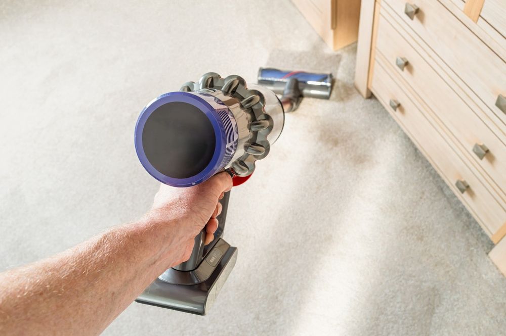 Handheld Vacuum Cleaning a Carpet Near a Wooden Dresser — A.S.A.P. Appliance Service & Sales in Lake Macquarie, NSW