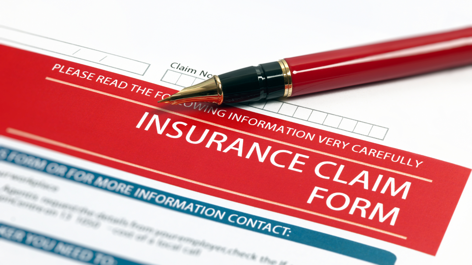 Red insurance claim form with a pen on top.