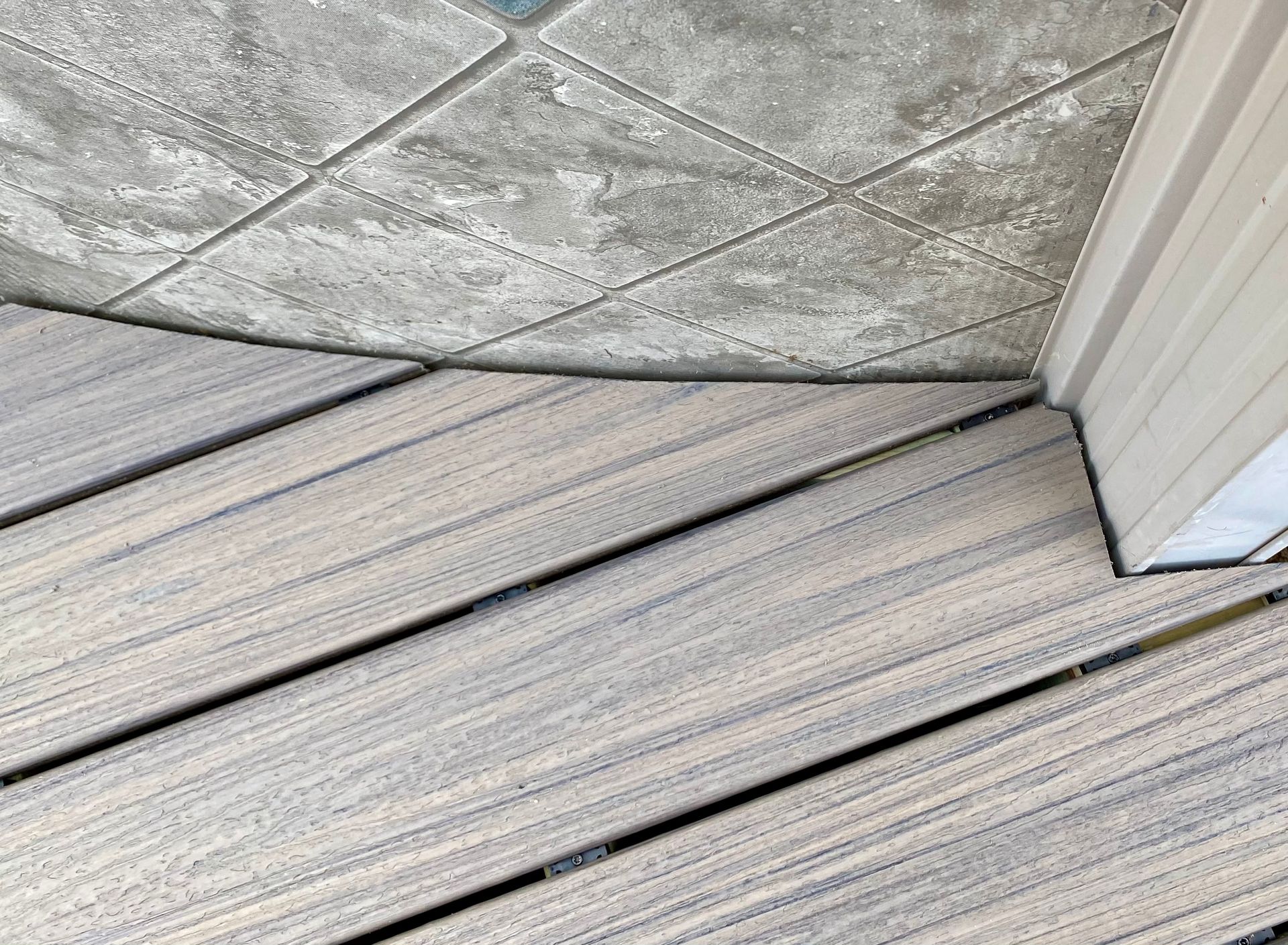 Gray wooden deck boards angled toward a corner with a concrete ceiling.