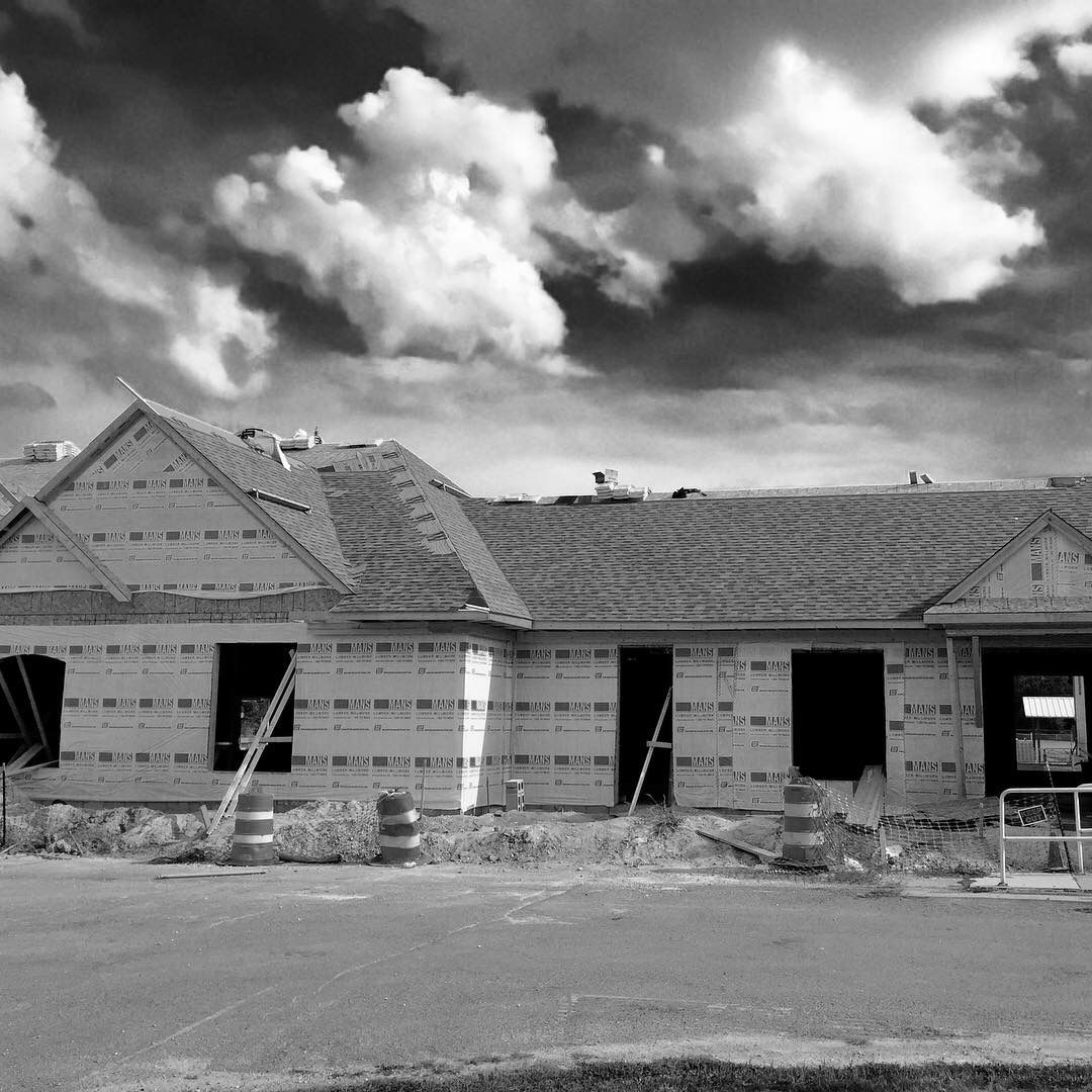 Unfinished house under construction, with dark cloudy sky overhead.
