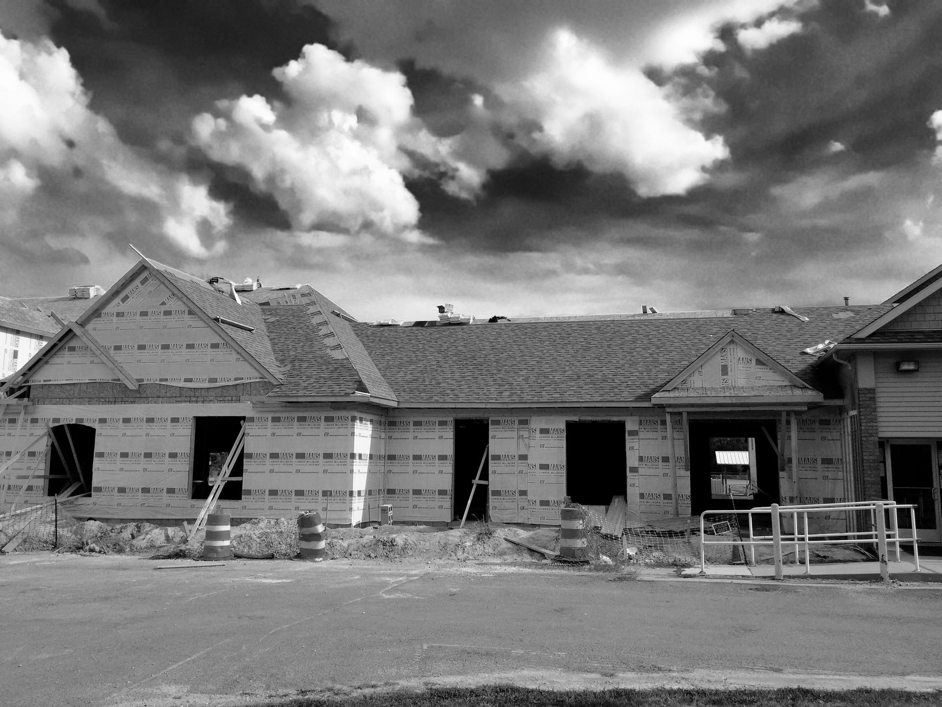Building construction site with exposed wooden frame and a cloudy sky.