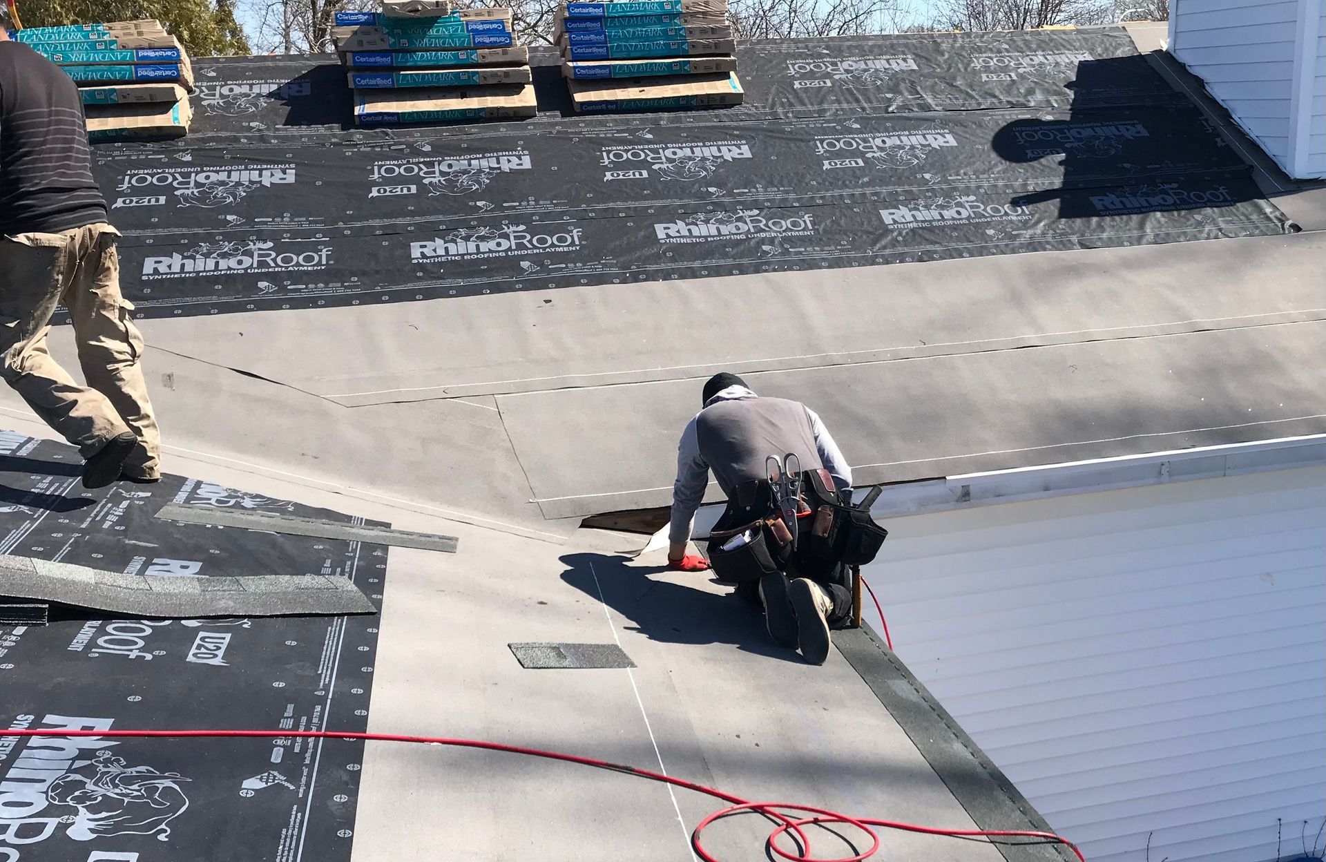 Two workers installing roofing materials on a house roof.