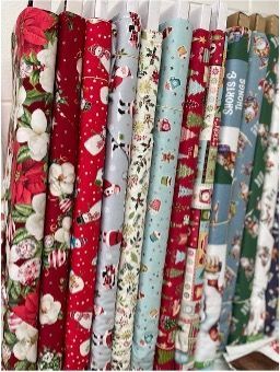 A Bunch of Christmas Fabrics Are Hanging on a Rack — Lyn-Jelle Crafts in Emu Park, QLD