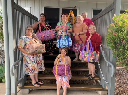 A Group of Women Are Standing on a Set of Stairs Holding Bags — Lyn-Jelle Crafts in Emu Park, QLD