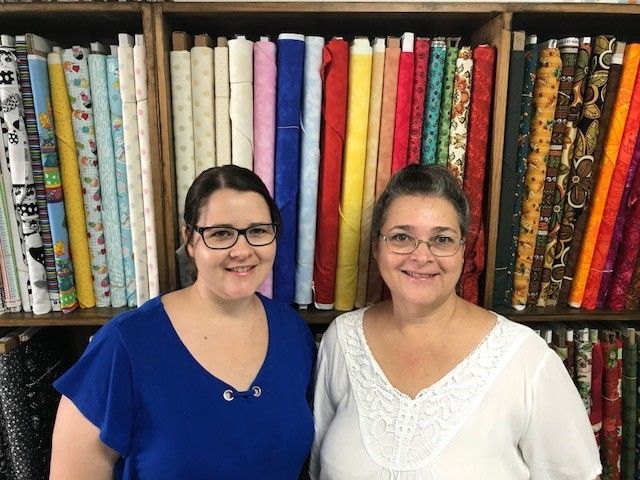 Two Women Are Standing Next to Each Other in Front of Fabric — Lyn-Jelle Crafts in Emu Park, QLD