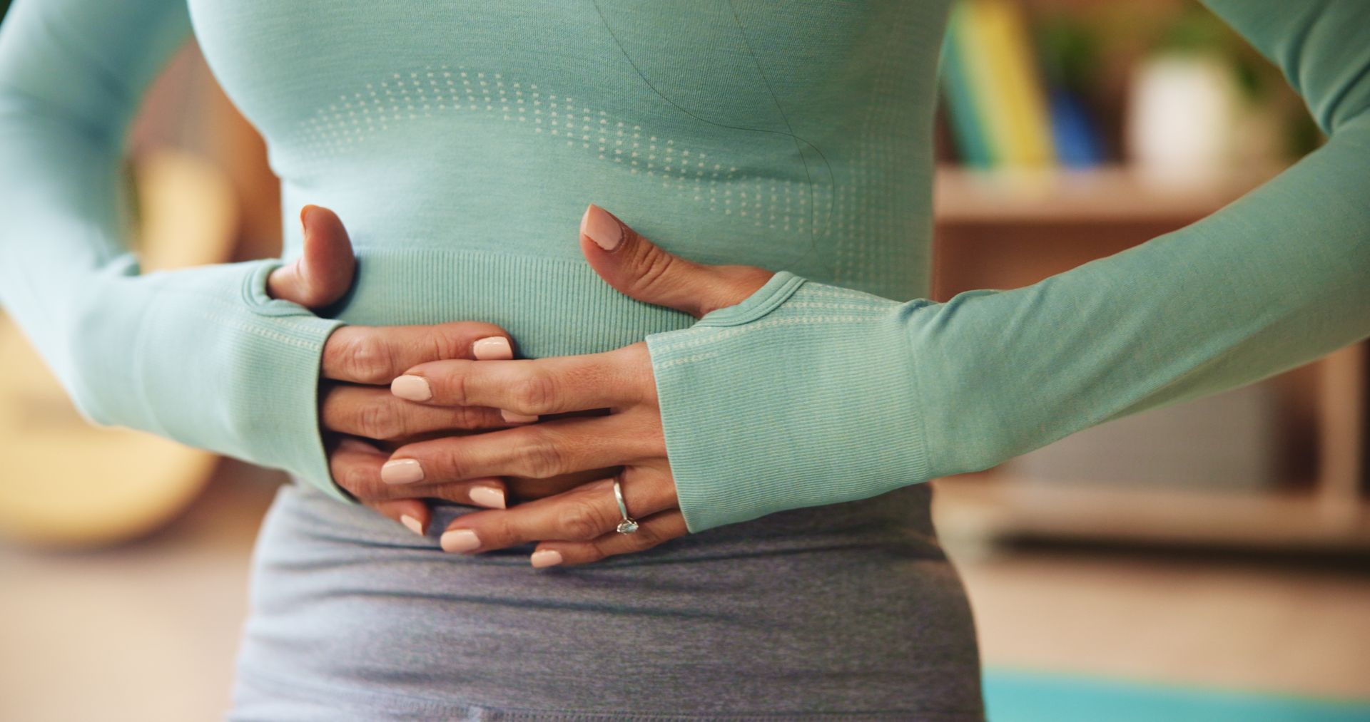 A woman is holding her stomach with her hands.
