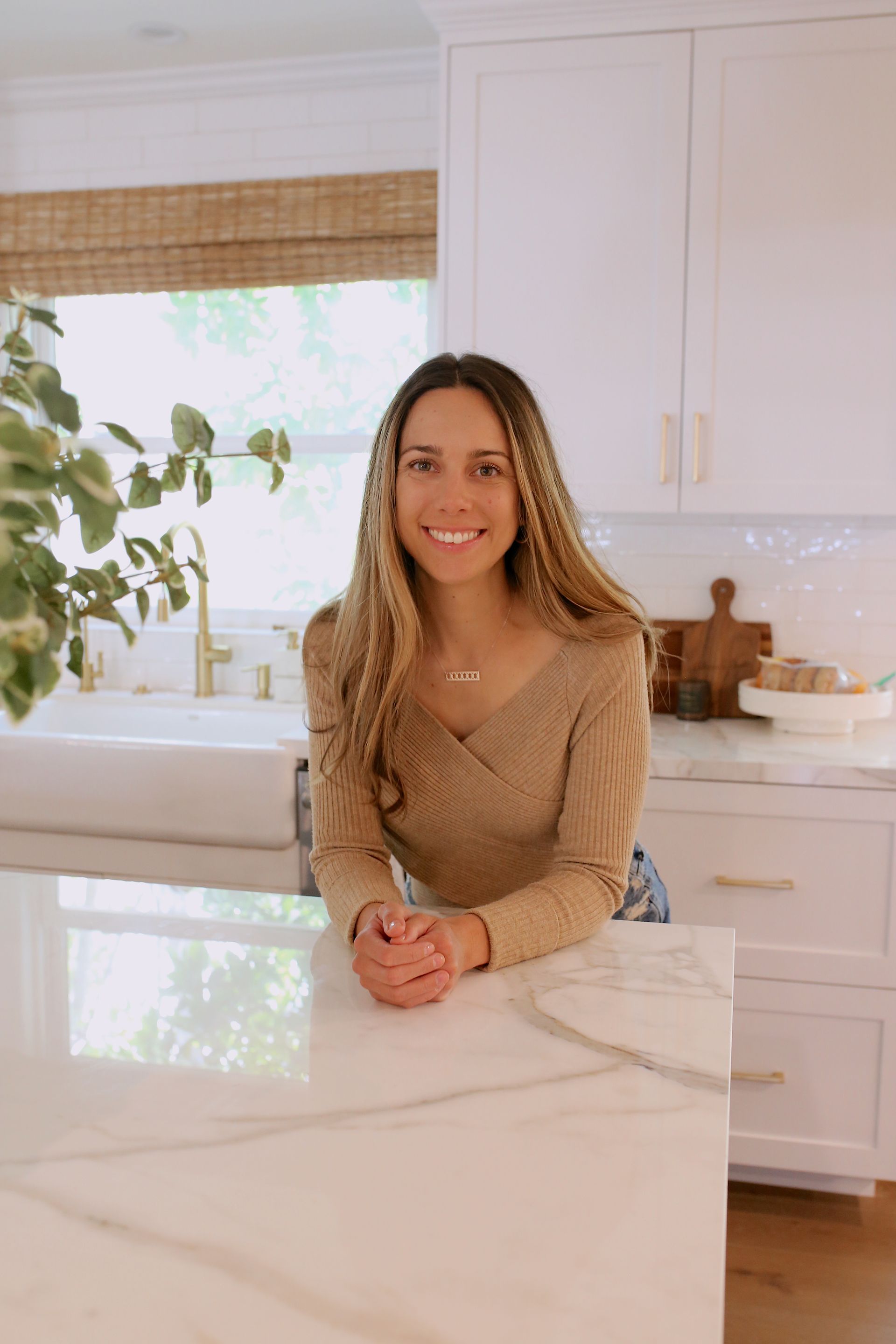 A woman is sitting on a counter in a kitchen.