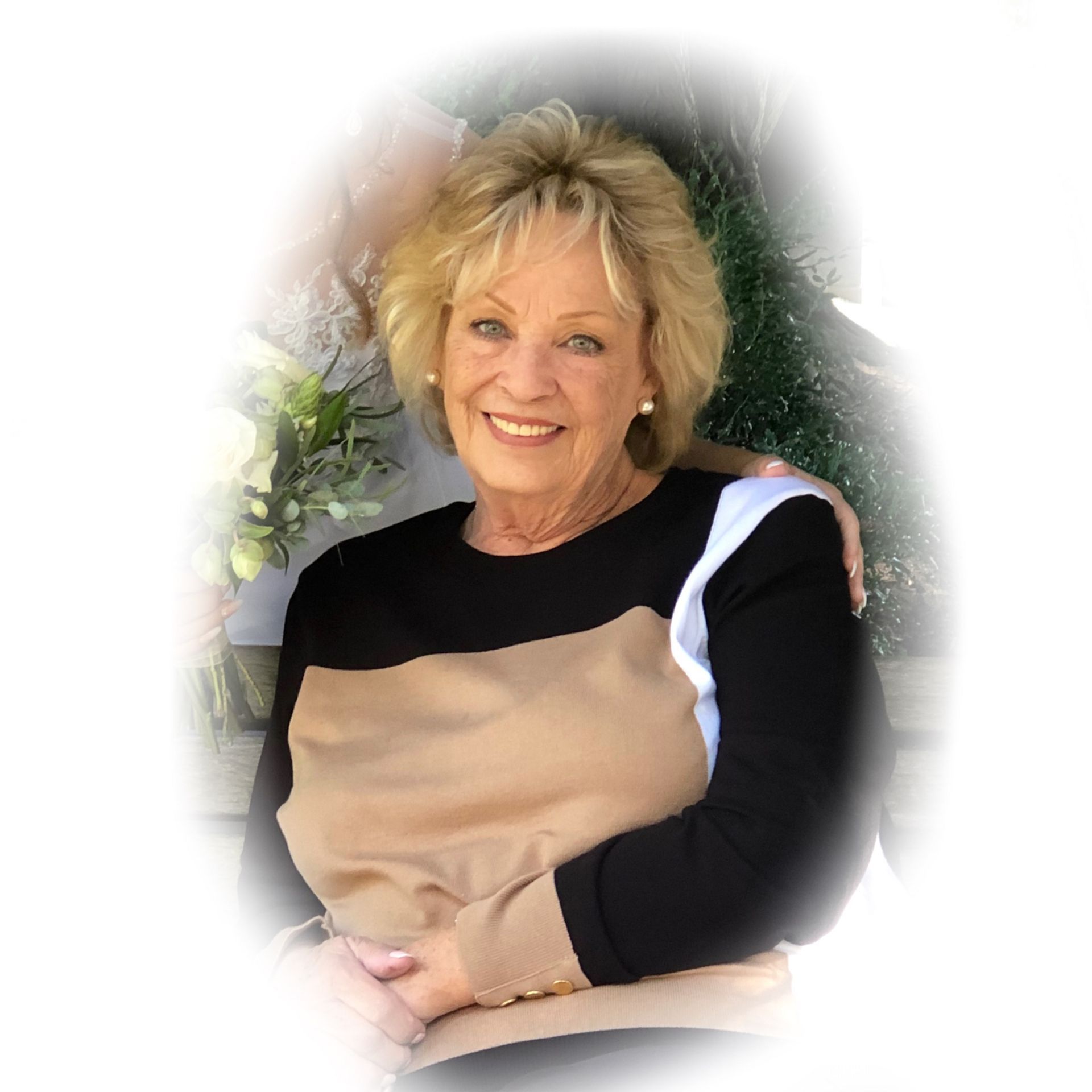 A woman in a black and tan sweater is smiling for the camera.