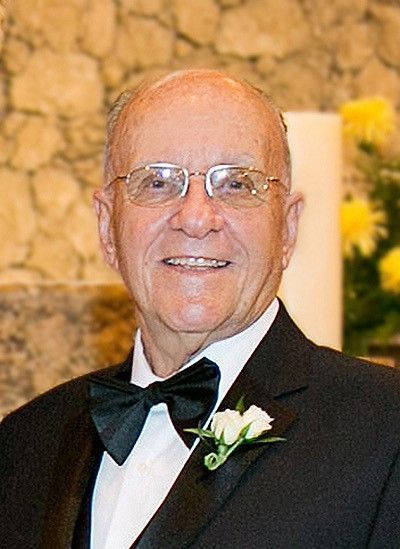 A man in a tuxedo and bow tie is smiling for the camera.