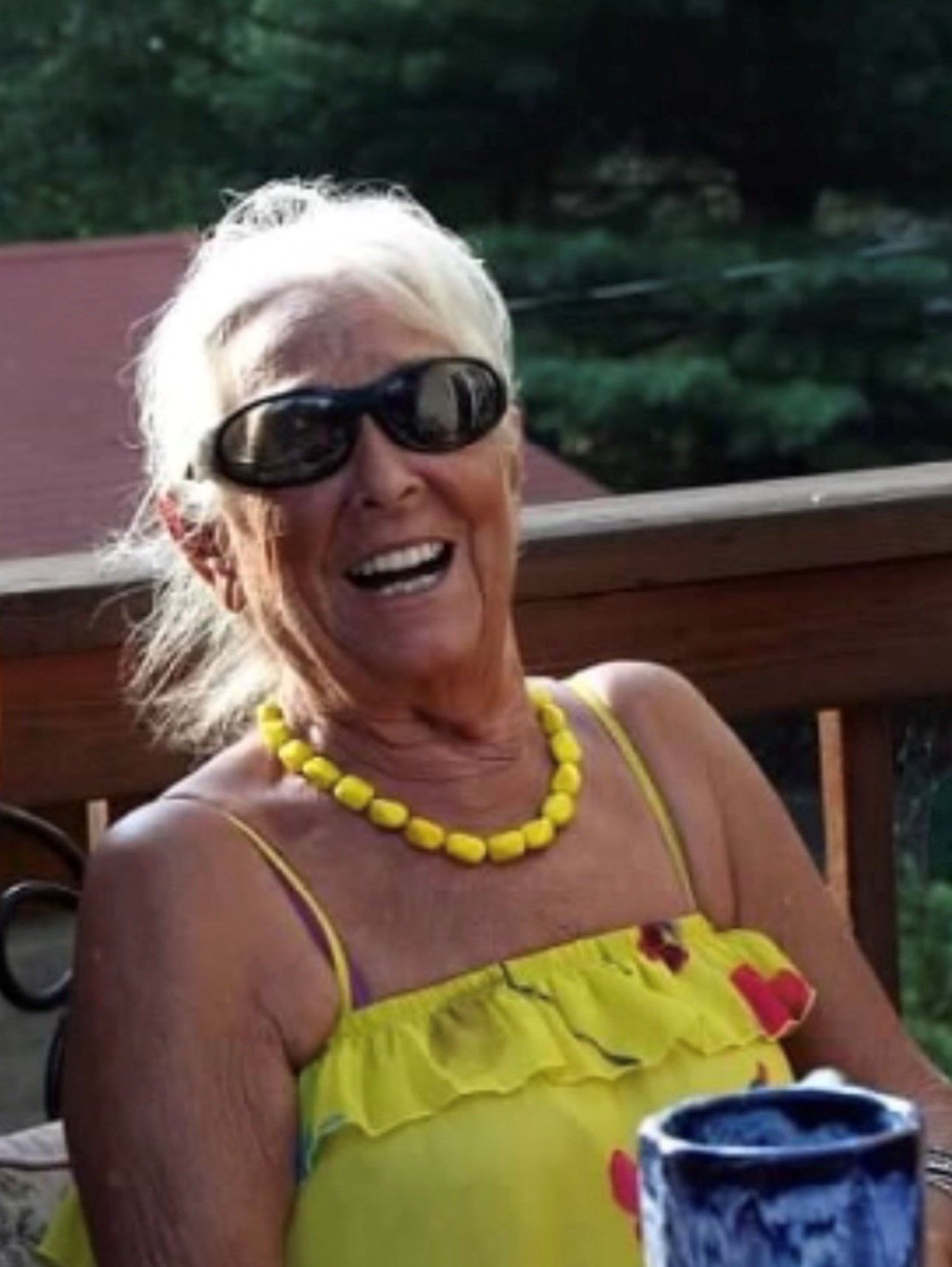 A woman wearing sunglasses and a yellow top is smiling